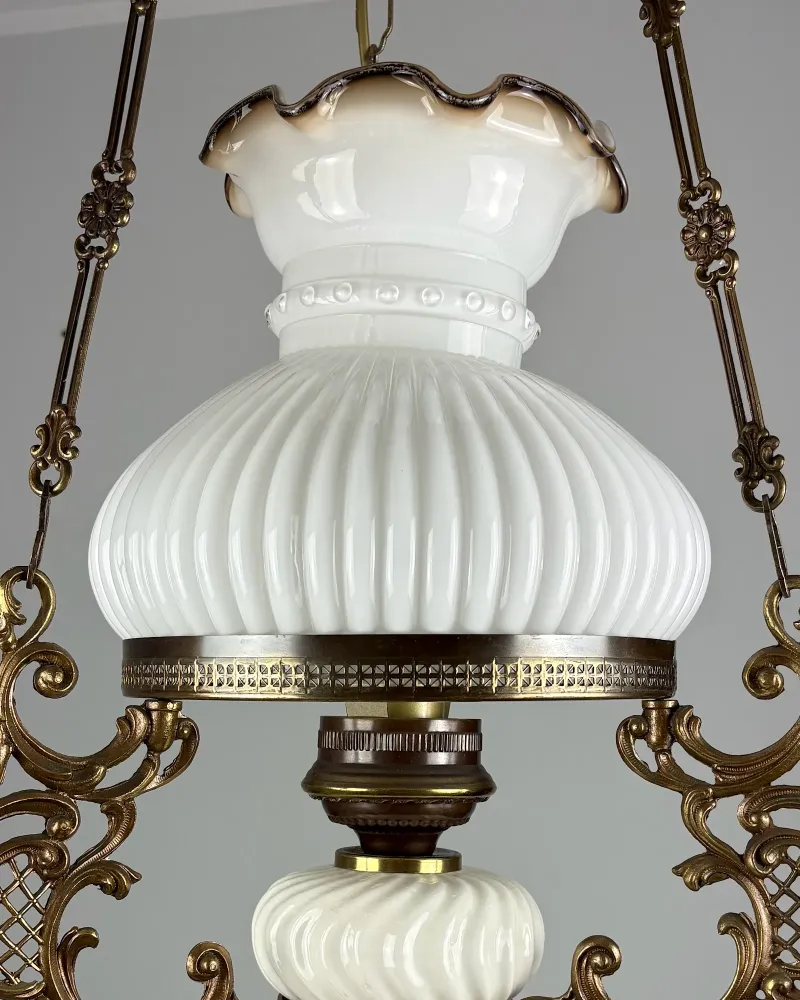Ruffled brown-shaded rim, beaded band and ribbed bell of the milk glass shade on a brass hanging lamp