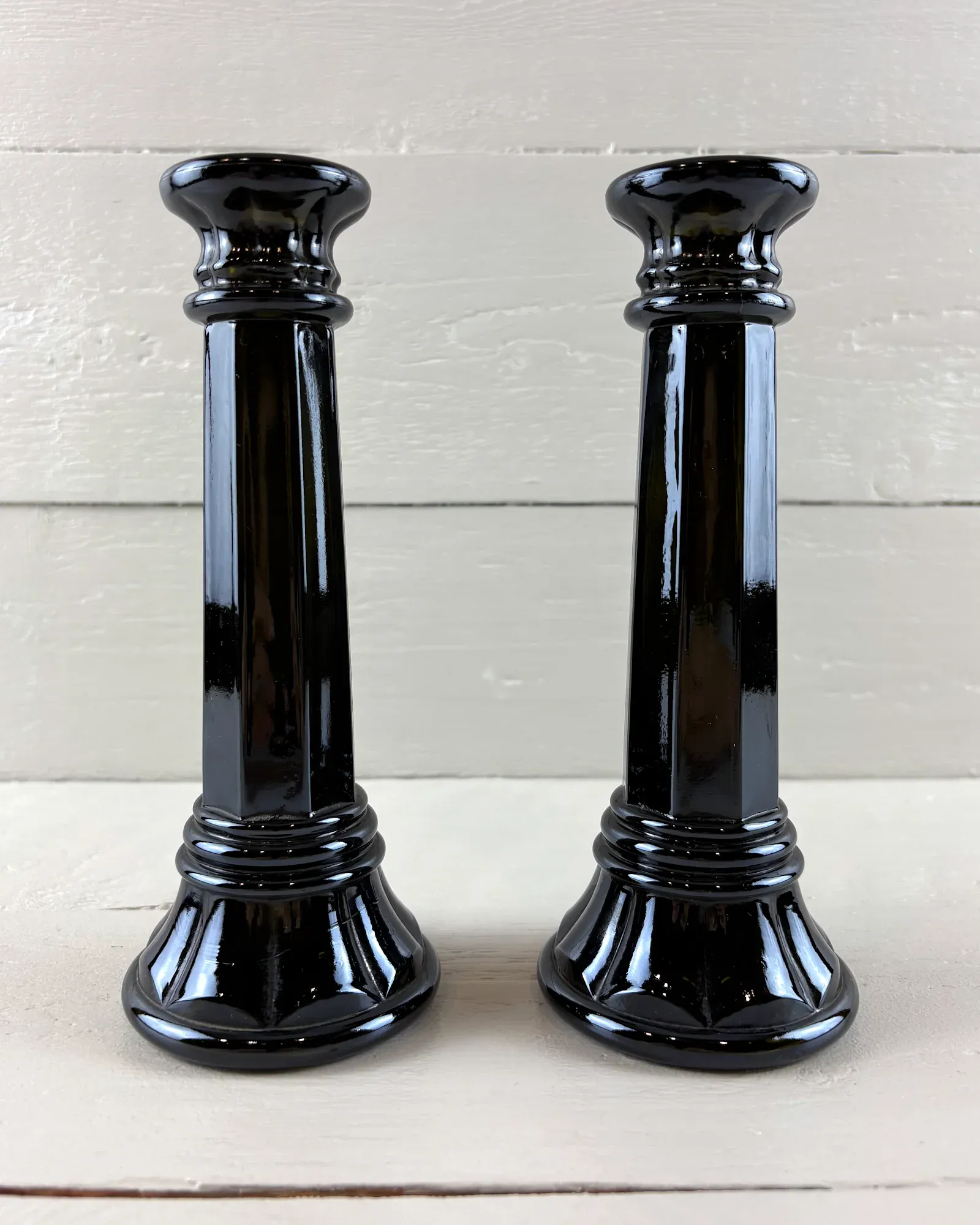 Pair of black pressed glass column candlesticks with octagonal shafts and fluted bases, front view