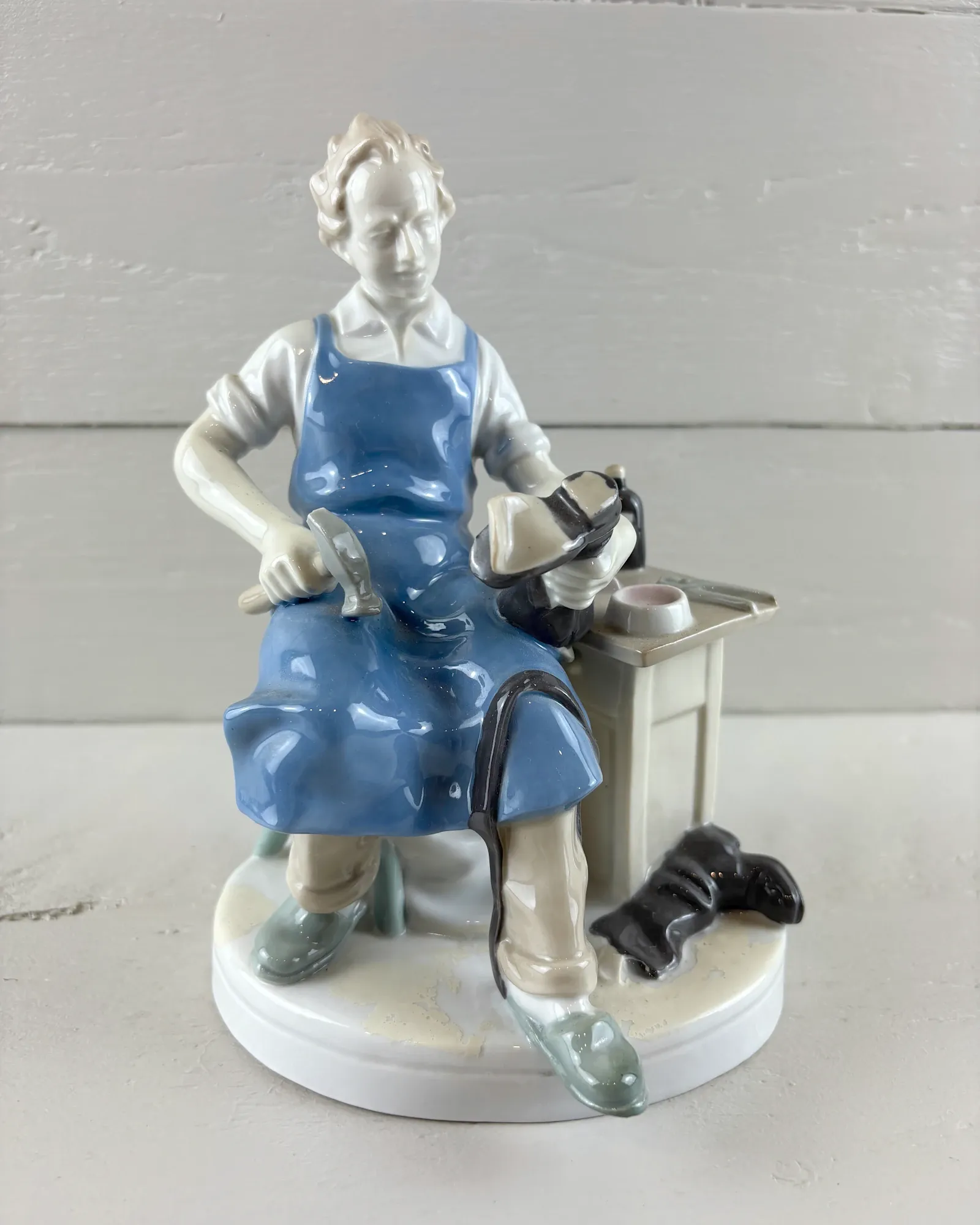 Porcelain cobbler figurine by Carl Scheidig, Grafenthal, front view with blue apron, hammer and boot on last