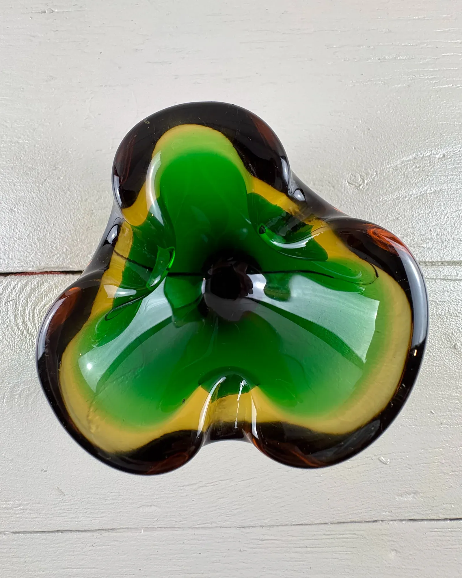 Mid-century Murano-style sommerso glass trefoil ashtray in green and amber, seen from above