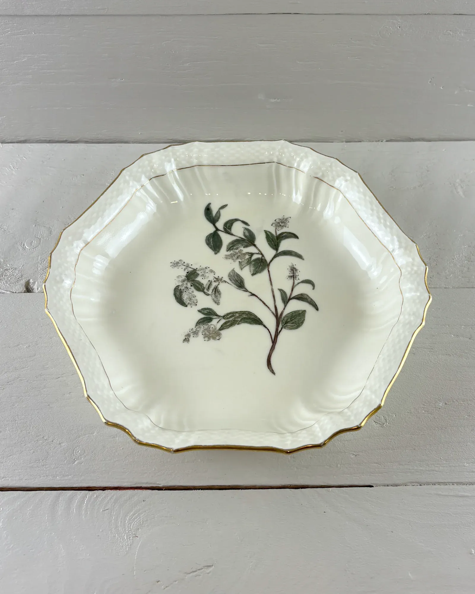 Royal Copenhagen hexagonal porcelain dish with gilt rim and green-grey botanical sprig, seen from above