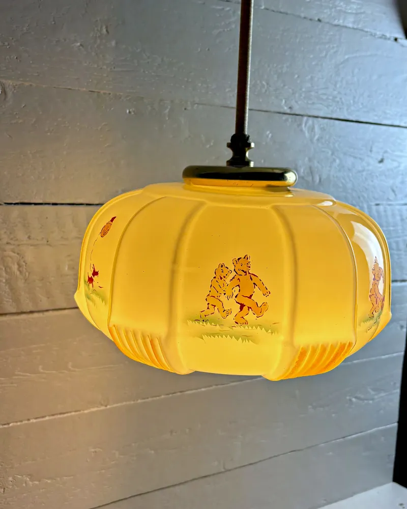 Side view of the opal glass bear lamp with two printed bears walking and amber ribbed feet under the shade