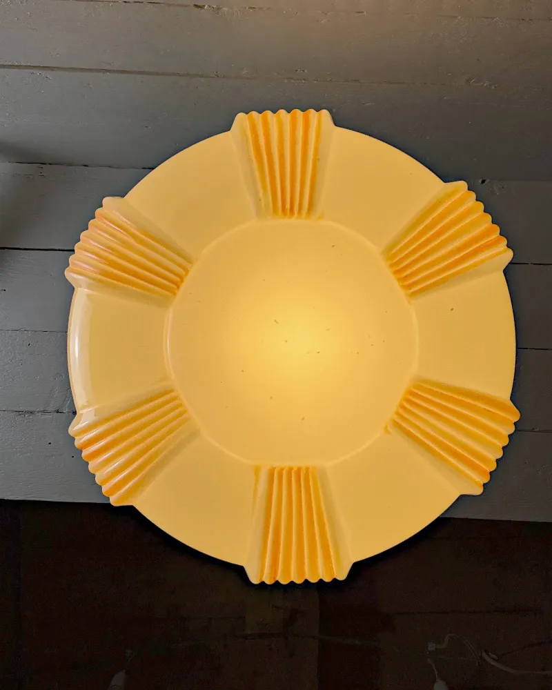 Underside of the opal glass pendant shade with six groups of amber ribbed feet around a pale centre