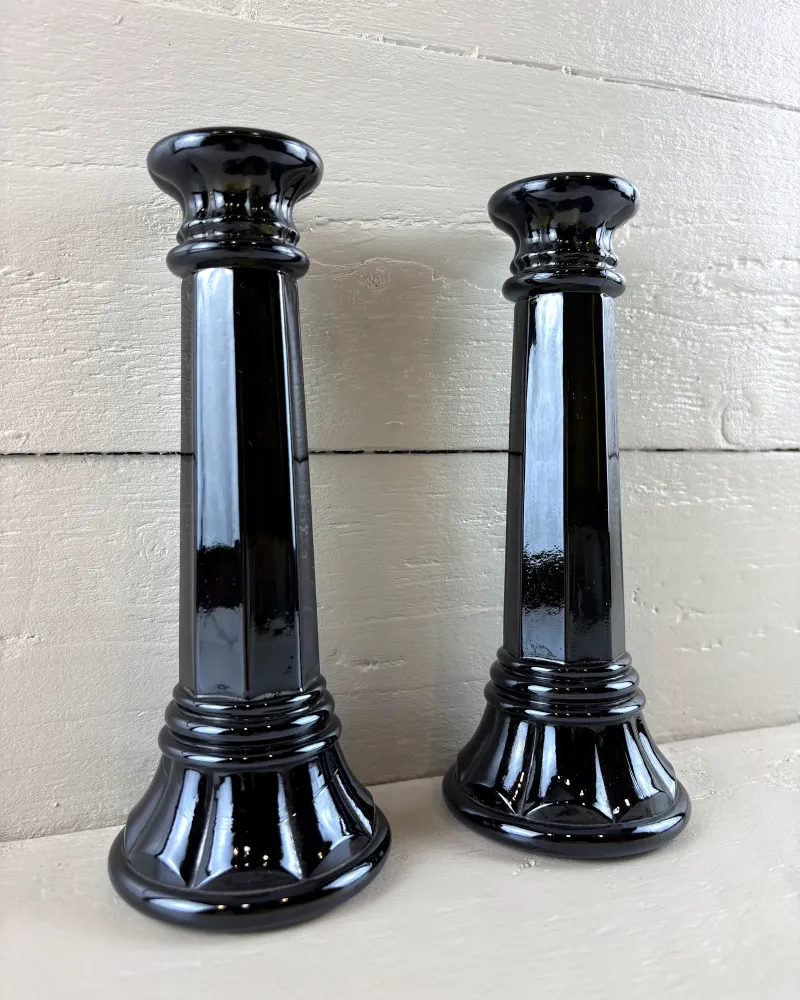 Black glass column candlesticks from a low three-quarter angle, showing the tapered octagonal stems