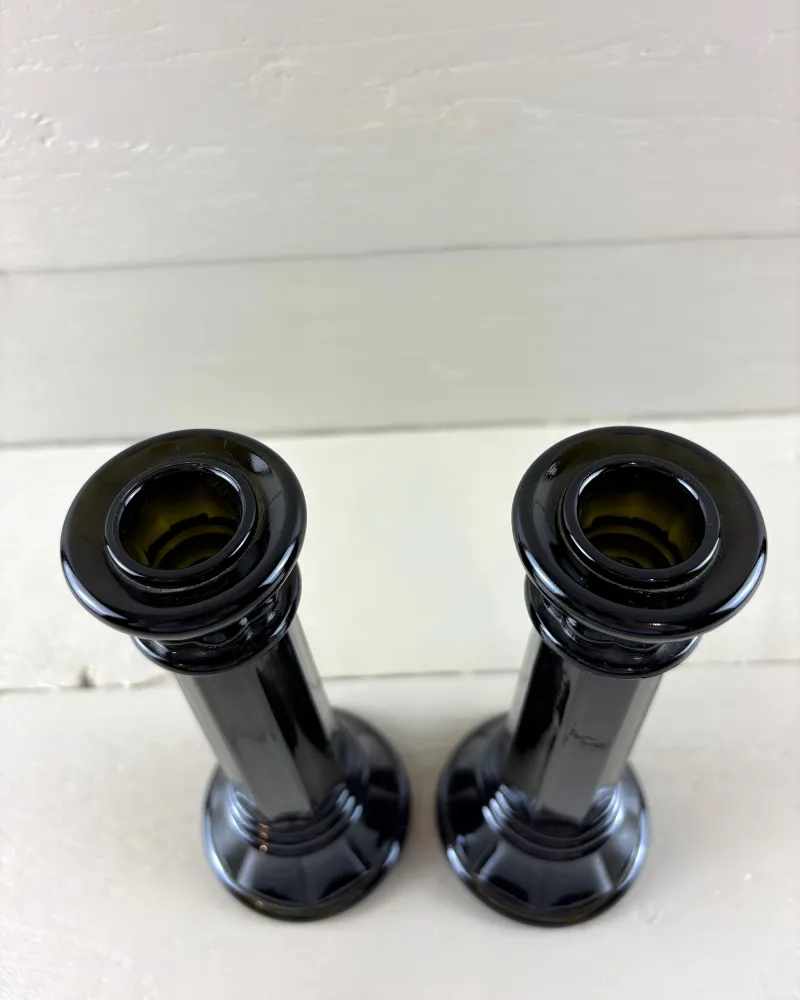 View from above into the candle cups of two black glass candlesticks, olive green tint inside the sockets