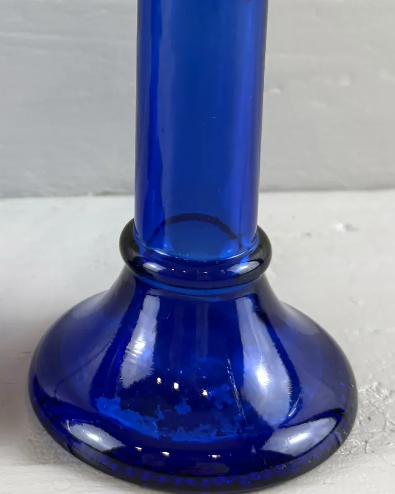 Close-up of a cobalt blue glass candlestick foot showing frosted patches on the glass surface