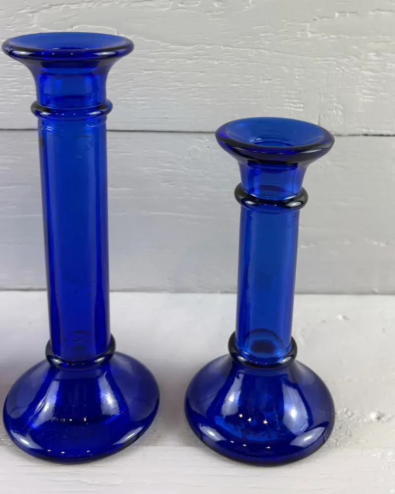 Two cobalt blue glass candlesticks with ringed stems and flared cups on domed feet, front view