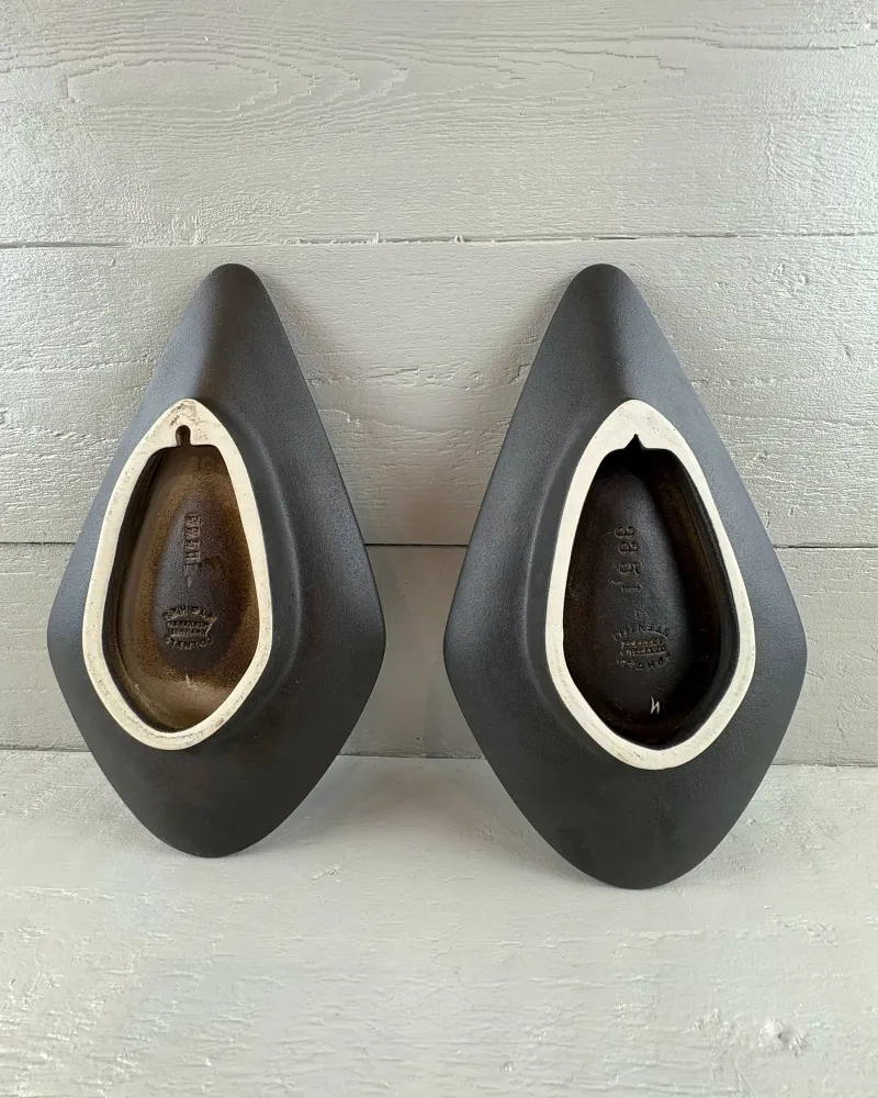 Unglazed dark backs of two Soholm 3351 wall candle holders with white rims and hanging notches