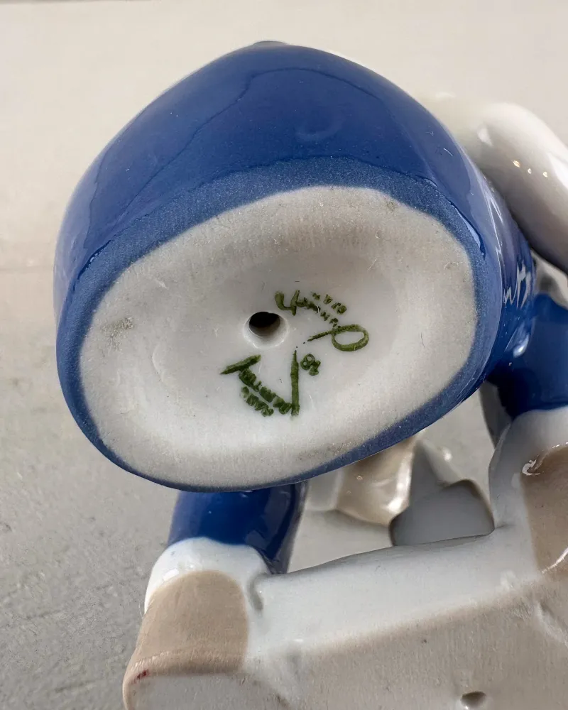 Unglazed base of a porcelain figurine with a firing hole and green marks inside a blue rim