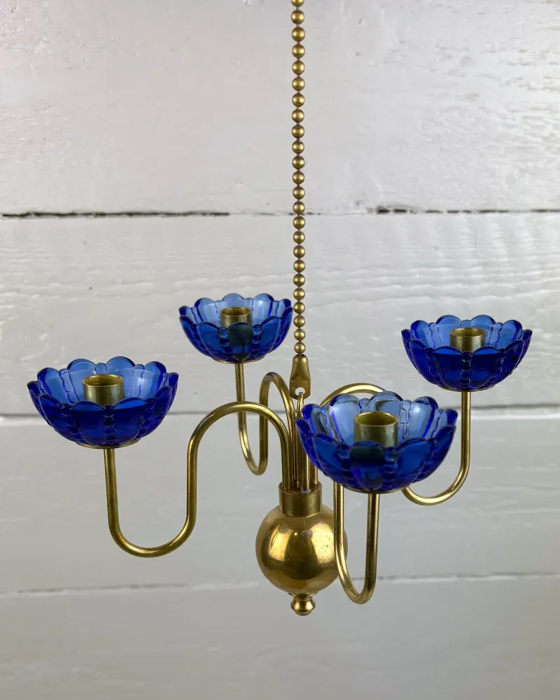 Close-up of blue moulded glass cups and curved brass arms on a 1950s Ystad Metall candelabra
