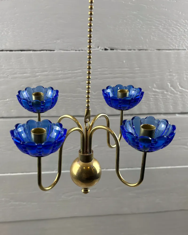 Brass arms meeting at the hook and sphere of a Gunnar Ander candelabra, seen from the front