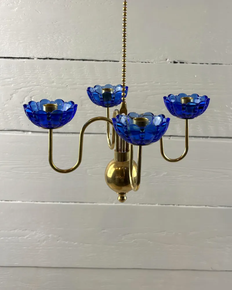 Side view of the Ystad Metall hanging candelabra showing S-shaped brass arms and brass sphere