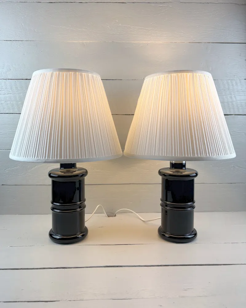 Pair of Holmegaard Apotheker table lamps lit, with pleated white shades that are illustrative only
