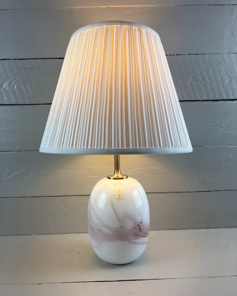 Holmegaard Sakura table lamp by Michael Bang switched on, shown with an illustrative pleated shade