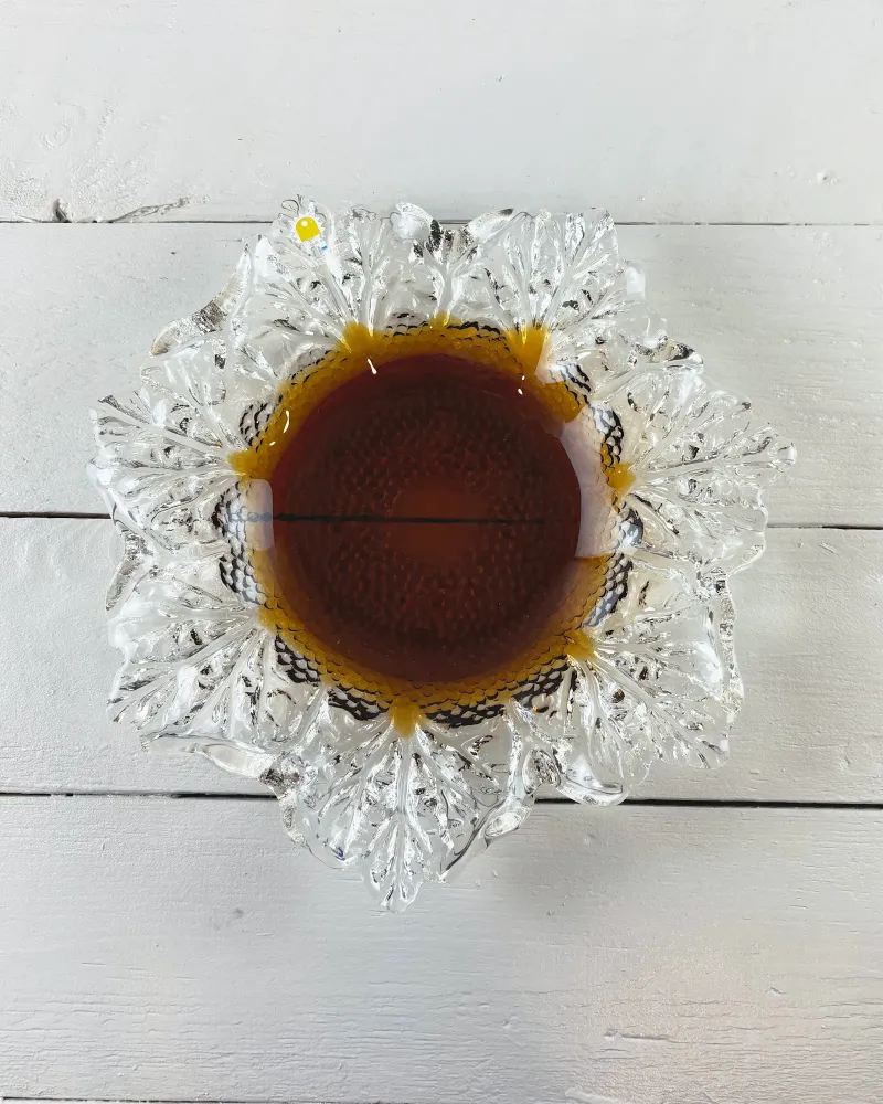 Top view of Humppila Kasvimaalla bowl: star-like ring of veined clear glass leaves around a round amber centre