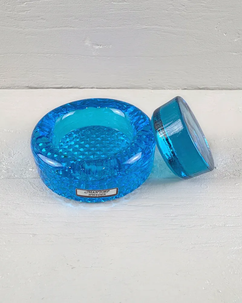 Mantorp blue glass paperweight base seen at an angle, showing the studded recess and thick ribbed rim