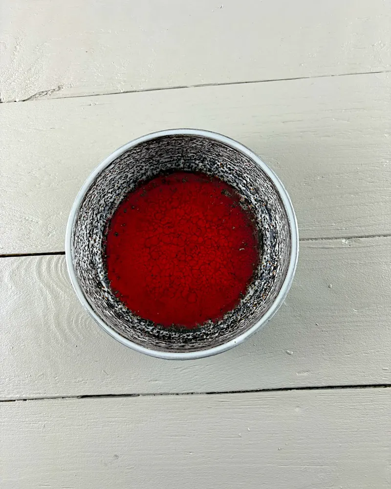 Top view of the Mari Simmulson Gloria bowl: deep red glaze framed by a white and brown speckled inner wall