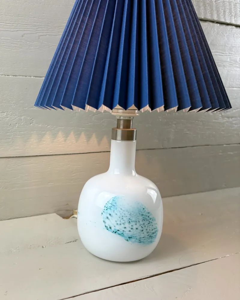 Michael Bang Holmegaard opal glass lamp seen at an angle, turquoise speckled patch on the rounded body