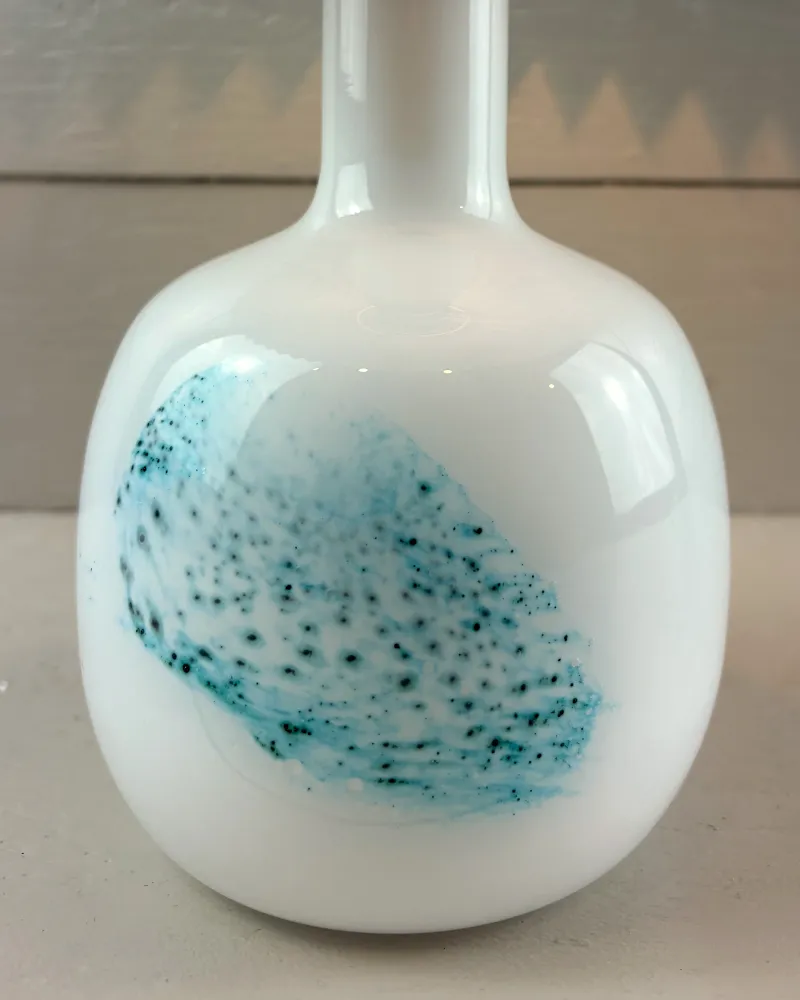 Close-up of the turquoise speckled glass decoration cased under the glossy white opal surface of the lamp