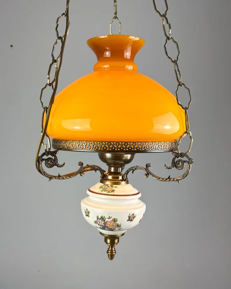 Oil lamp style brass pendant light with amber opal glass shade and floral ceramic font, front view