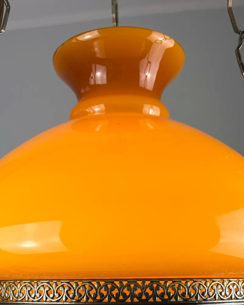 Close-up of the flared collar and amber opal glass shade of a vintage oil lamp style pendant