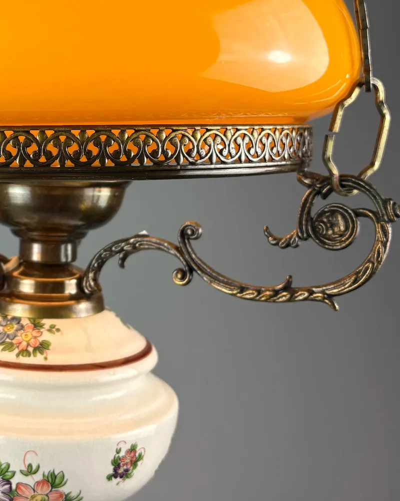 Cast brass scroll arms and pierced gallery above the floral ceramic font of a vintage pendant lamp