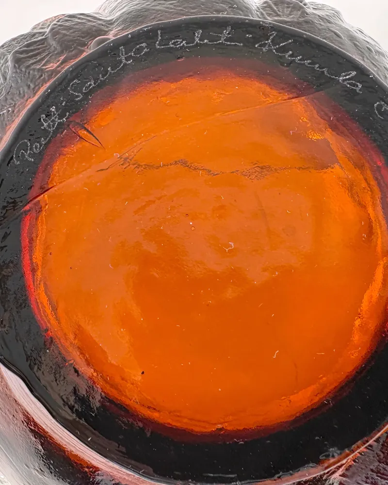 Engraved signature Pertti Santalahti Kumela on the dark amber base of the Kyyhky glass bowl