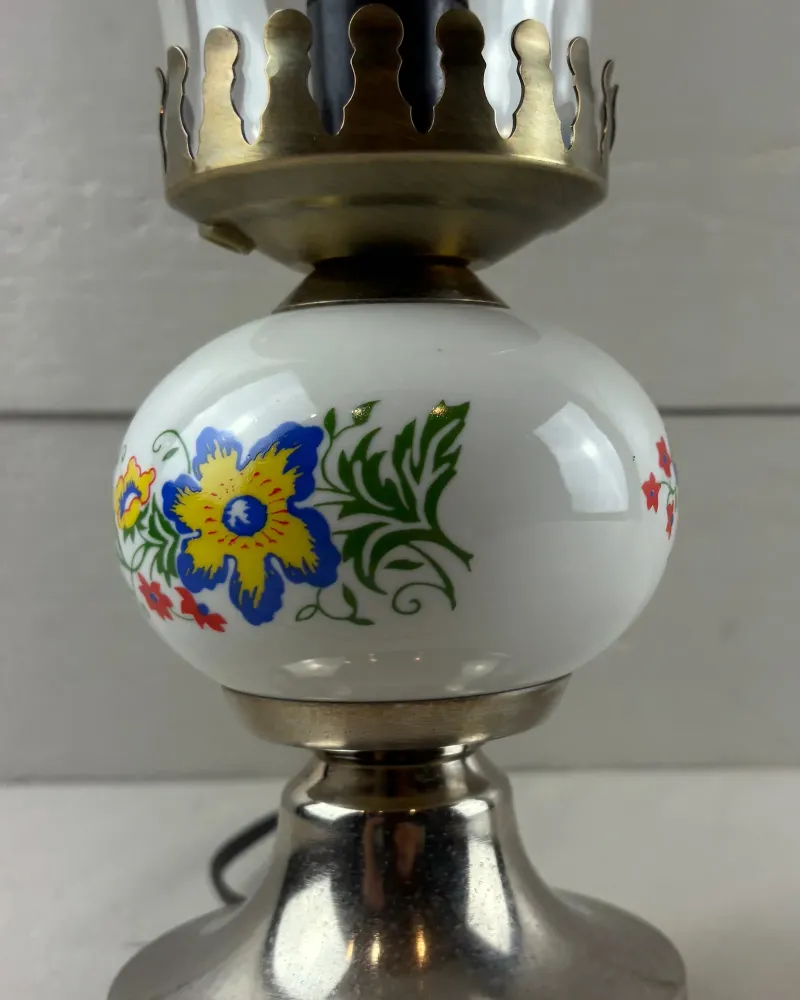 Close-up of the large blue and yellow flower and green leaves on the glossy ceramic globe of the lamp