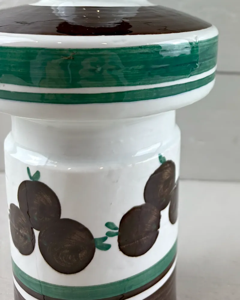 Close-up of hand-painted brown fruits and green bands on the white-glazed body of a Rorstrand lamp base