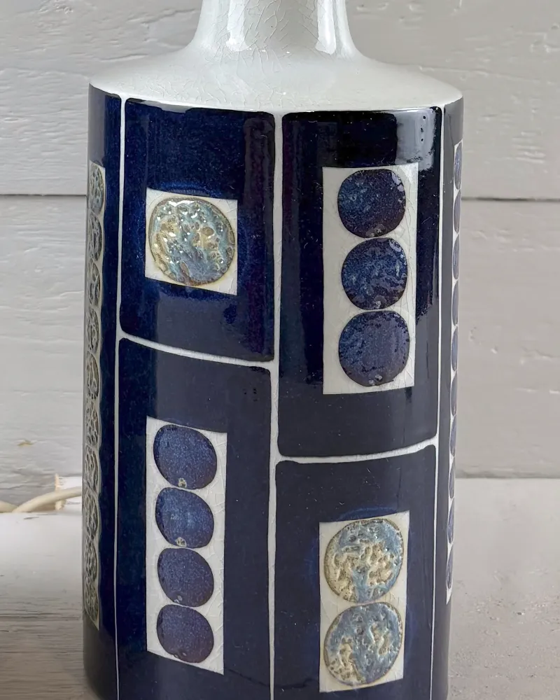 Close-up of hand-painted circles and dotted columns in blue, ochre and white on a Tenera ceramic lamp body