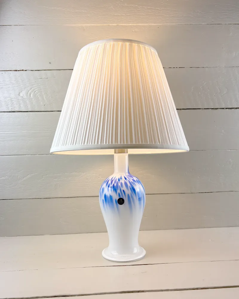 Royal Copenhagen Torino Mellem glass lamp switched on, warm light through the illustrative pleated shade