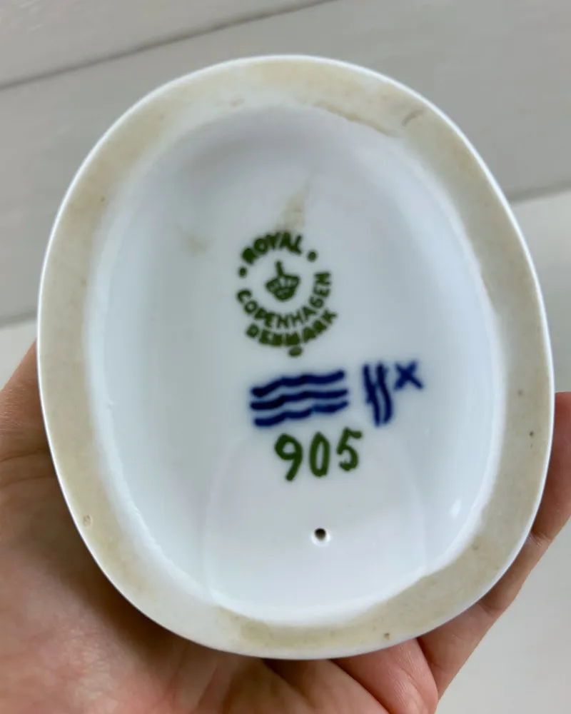 Underside of Royal Copenhagen Whittler figurine with green crown stamp, blue waves mark, model number 905 and vent hole