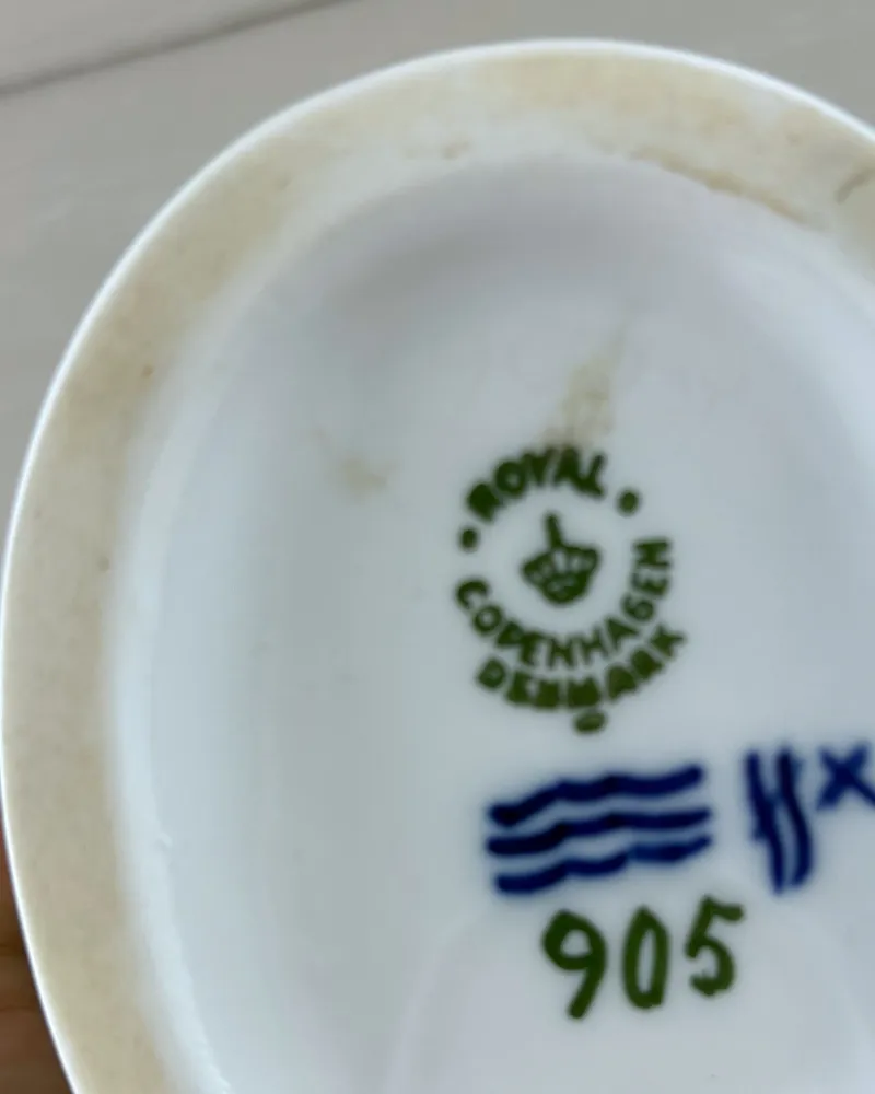 Close-up of the foot rim of a Royal Copenhagen figurine with brownish age staining beside the factory stamp
