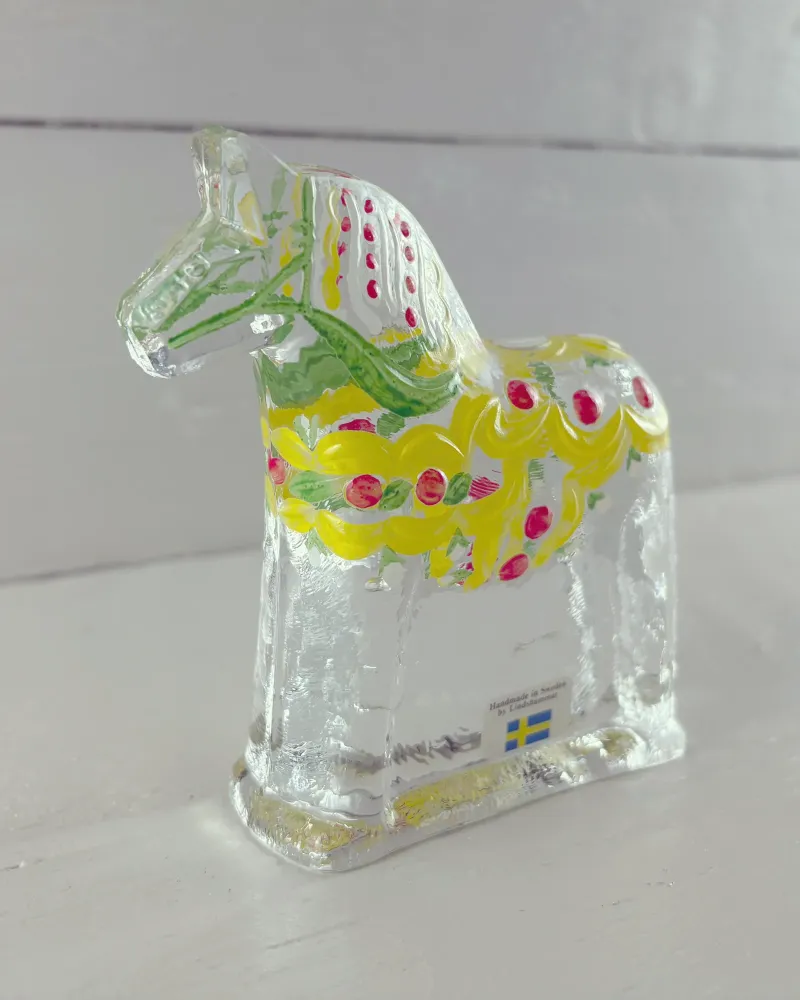 Swedish Lindshammar glass Dala horse with yellow painted garland and red berries, three-quarter view