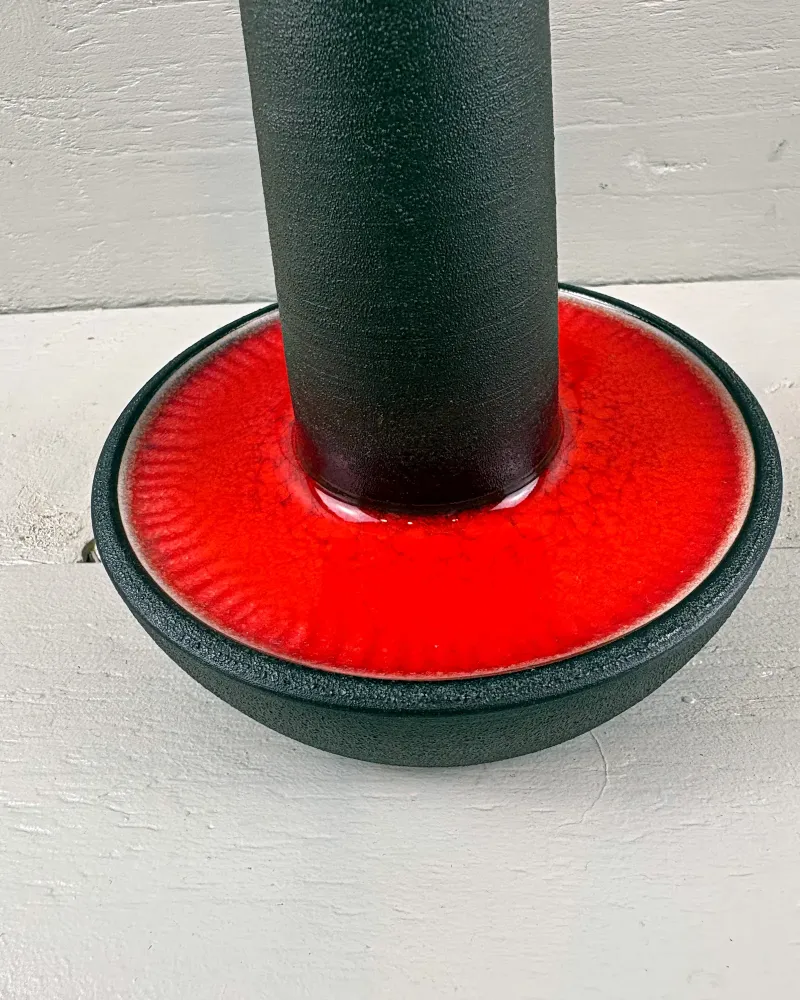 Close-up of red crackle glaze in the bowl-shaped foot of a Soholm 1072 table lamp, dark matte stem above