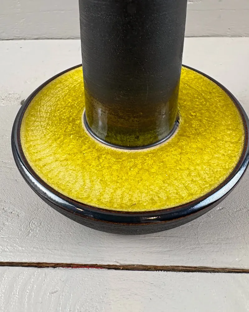 Close-up of yellow crackle glaze in the bowl-shaped foot of a Soholm 1072 table lamp, dark matte stem above