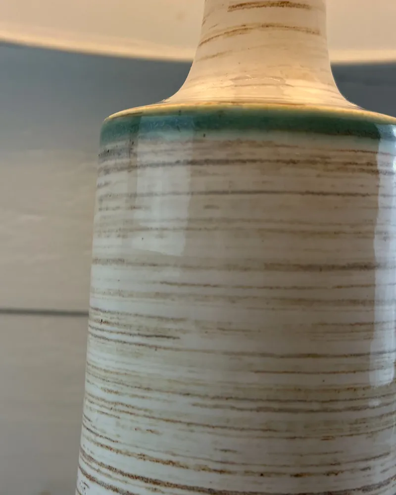 Close-up of the cream and brown streaked glaze and teal rim on a Danish Soholm lamp base