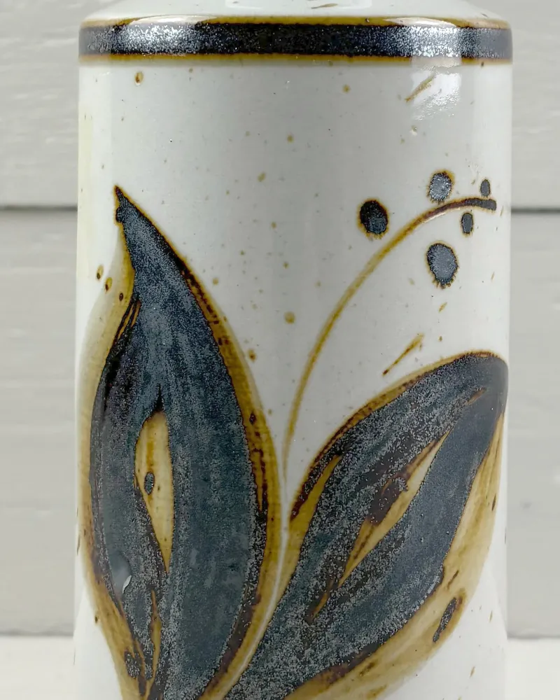 Close-up of painted leaves and berries on the speckled glaze of a Soholm Lilia stoneware lamp base