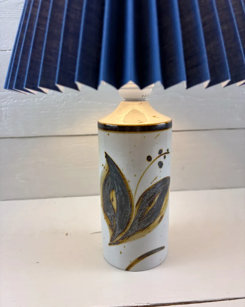 Soholm Lilia stoneware lamp with painted leaf motif under an illustrative blue pleated shade, close view