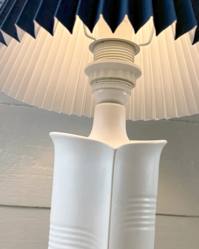 Socket fitting and shade holder above the white Soholm 1229 ceramic lamp base, lit, seen from a low angle