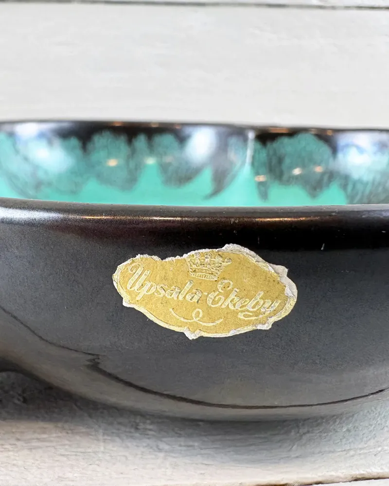 Side of black Upsala-Ekeby candle holder with original gold foil label and crown emblem
